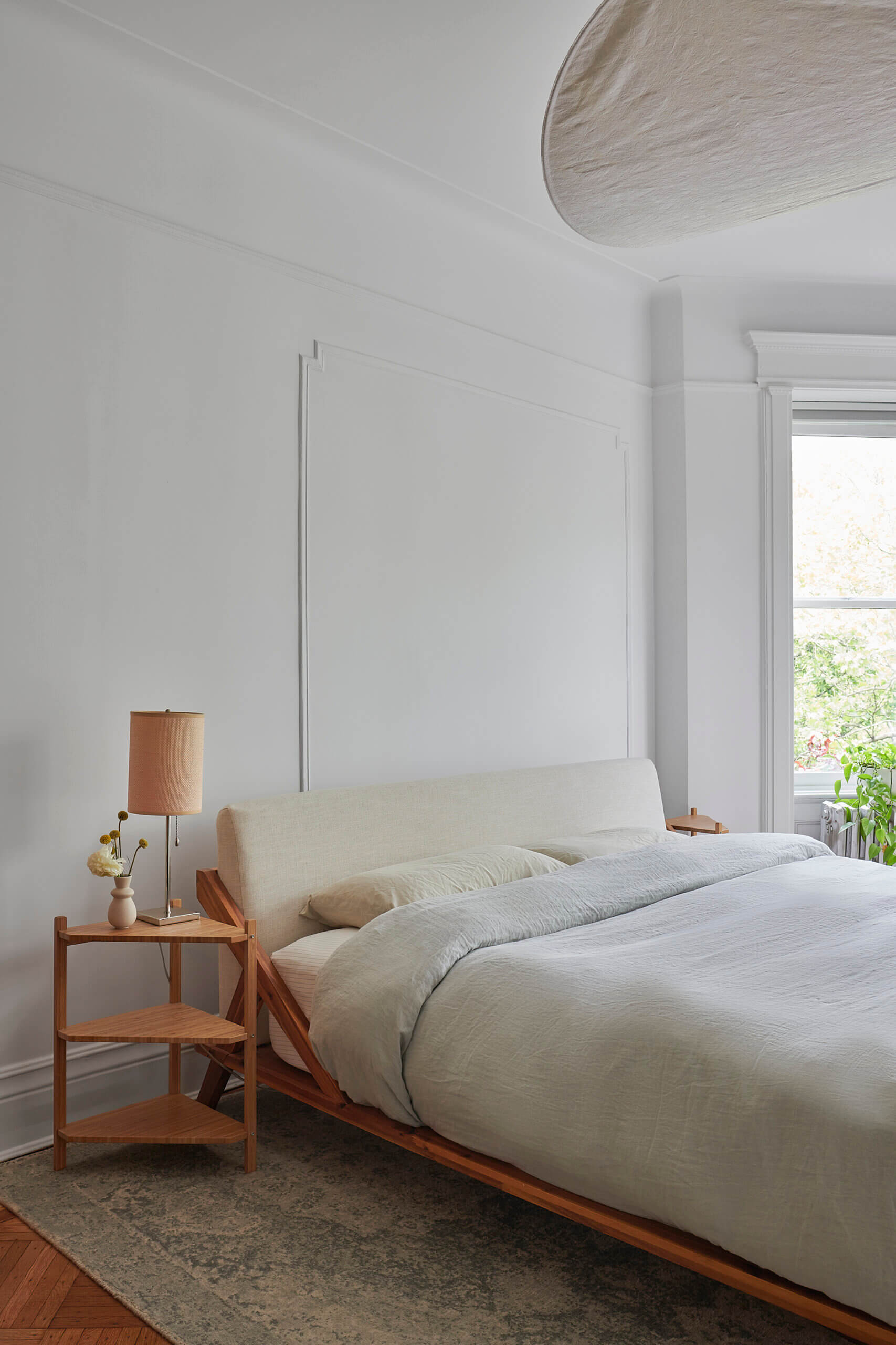 BEDROOM with a pale wood side table and a bed with neutral bed linens