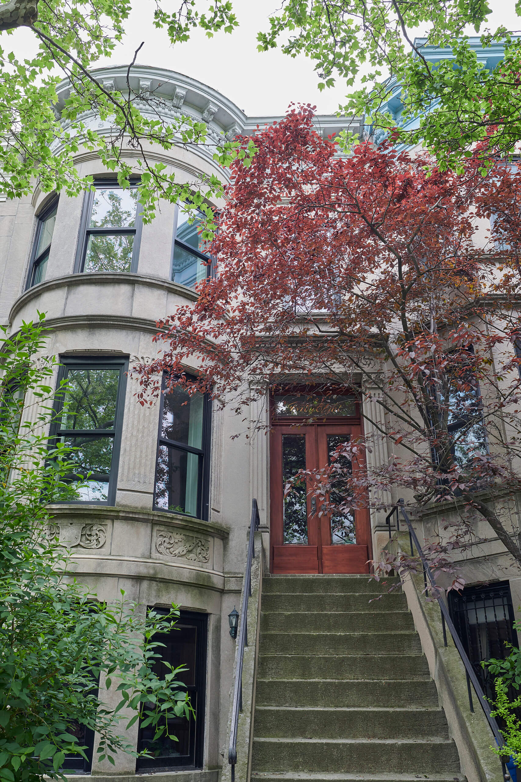 EXTERIOR of the limestone house with a stoop and a red door