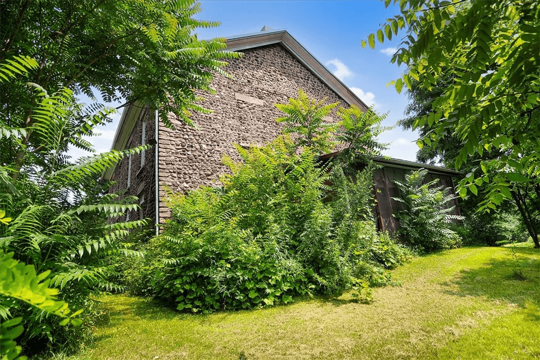 side facade of house showing some windows blocked with stone