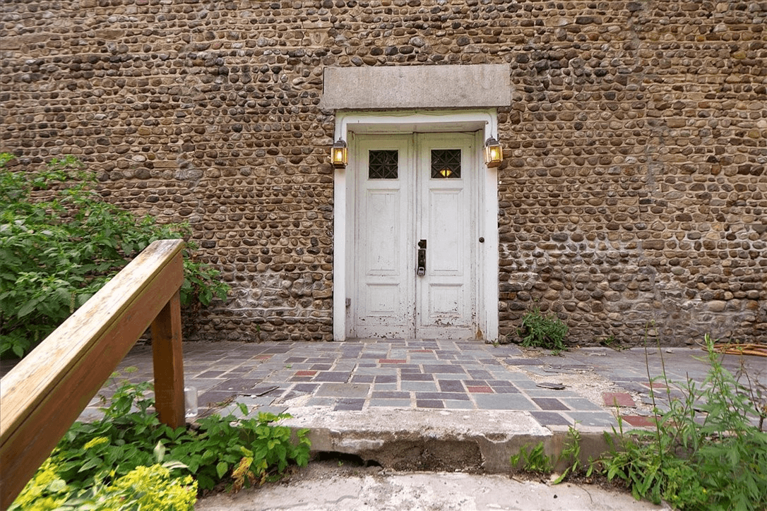 view to front door showing damaged concrete steps and broken pavers but original door lintel