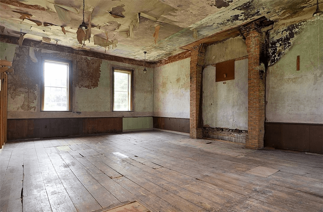 the original workship space with wood floors and a ceiilng with peeling paper