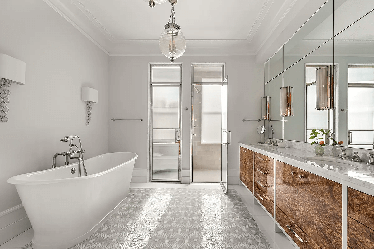 bathroom with soaking tub, double vanity and a mirrored wall