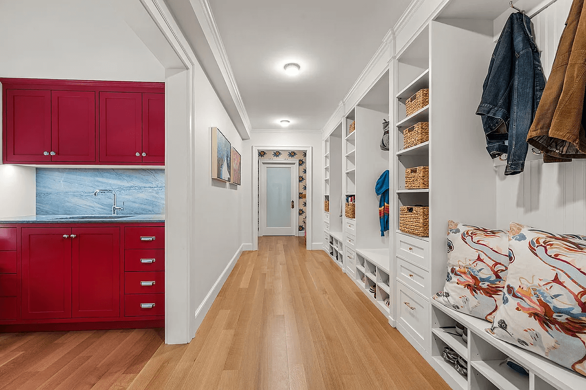 garden level hallway with built-in storage and view of red cabinets in laundry room