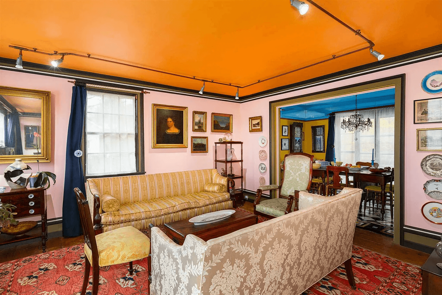 parlor with pink walls and orange ceiling and glimpse into dining room
