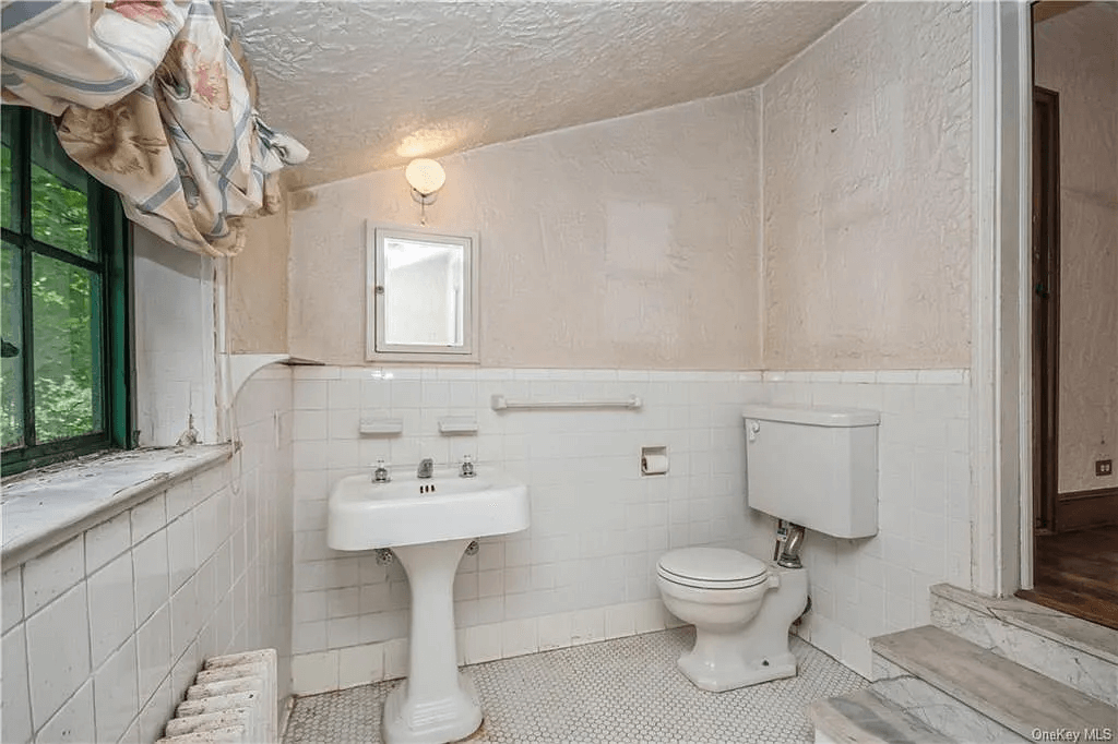 bathroom with steps down from bedroom and white tiles and fixtures