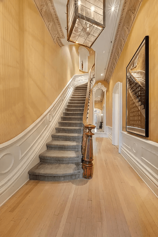 parlor level entry with original newel post, plasterwork and pale wood floors