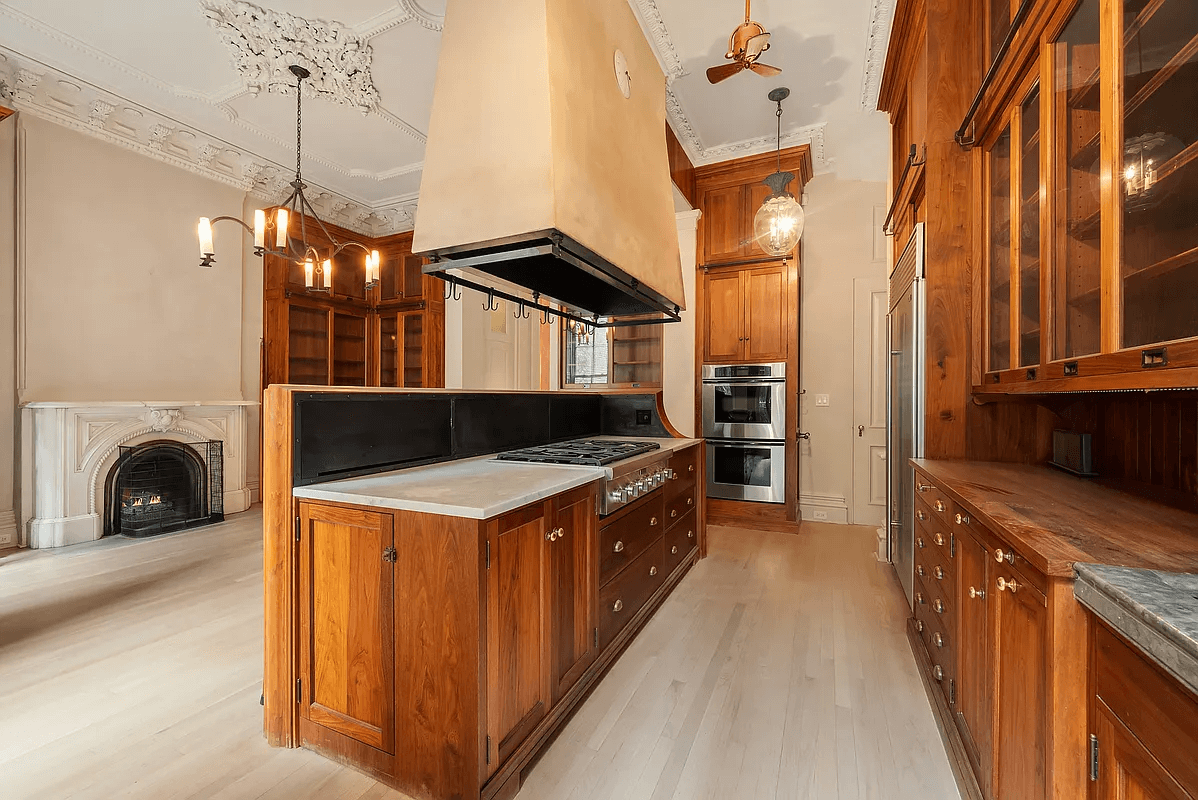 kitchen on parlor level with dark wood cabinets and a marble mantel in the dining area