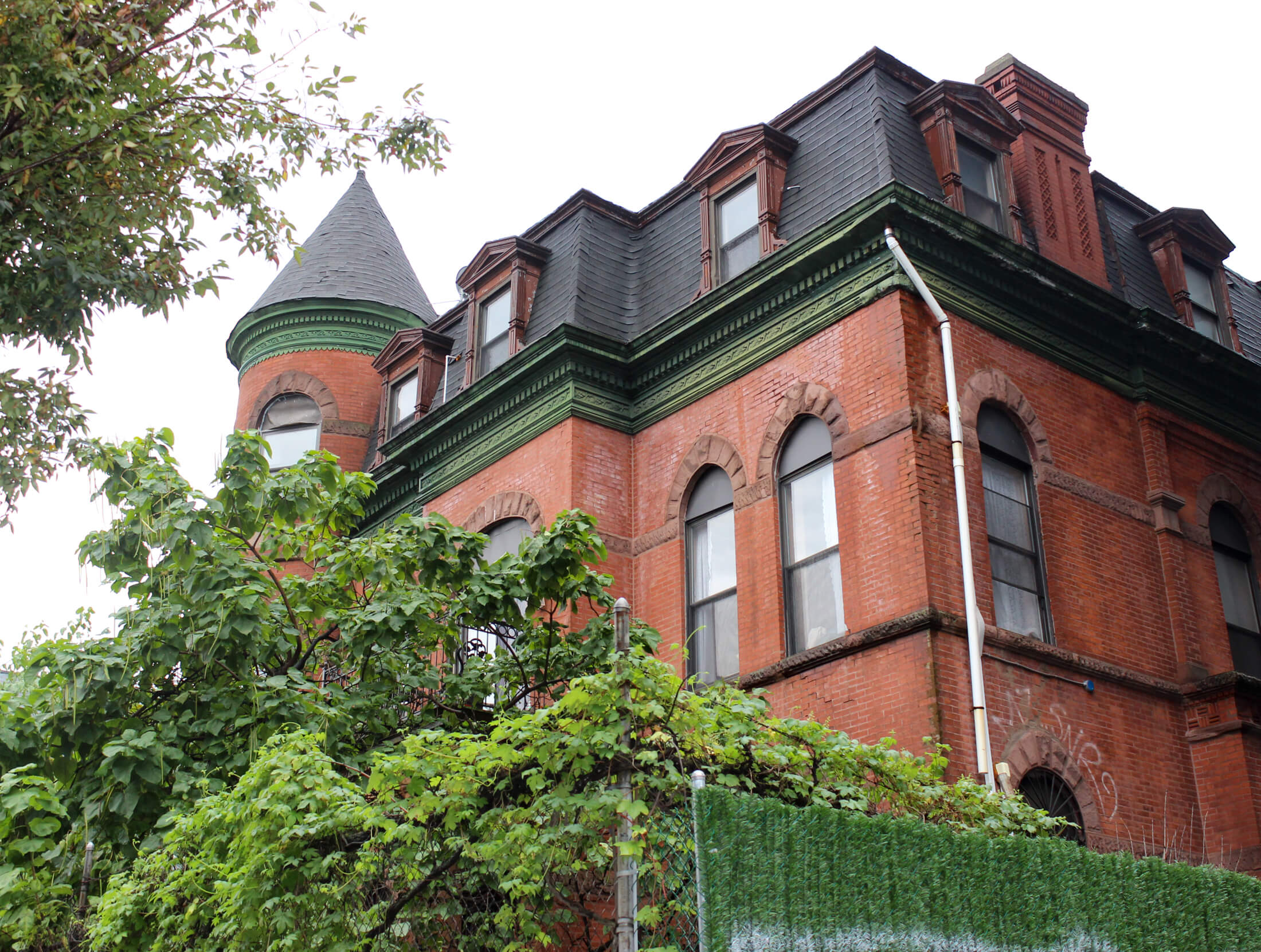 brick exterior of the mansion behind a chain link fence