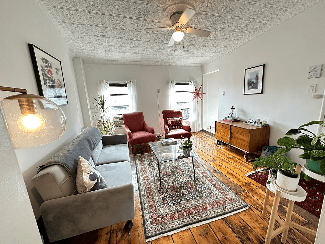 living room with two windows, tin ceiling and wood floors