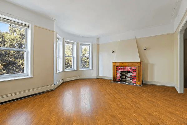room with a mantel, wood floors and baseboard heating
