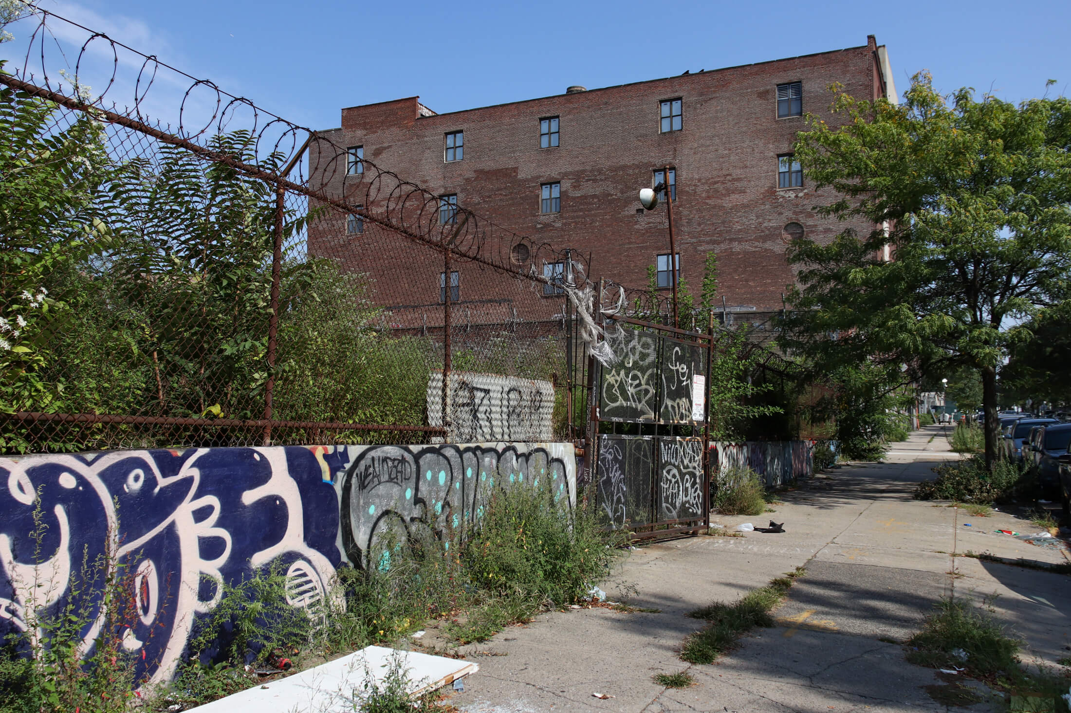 chain link fence and barbed wire surrounding an empty lot next to the factory