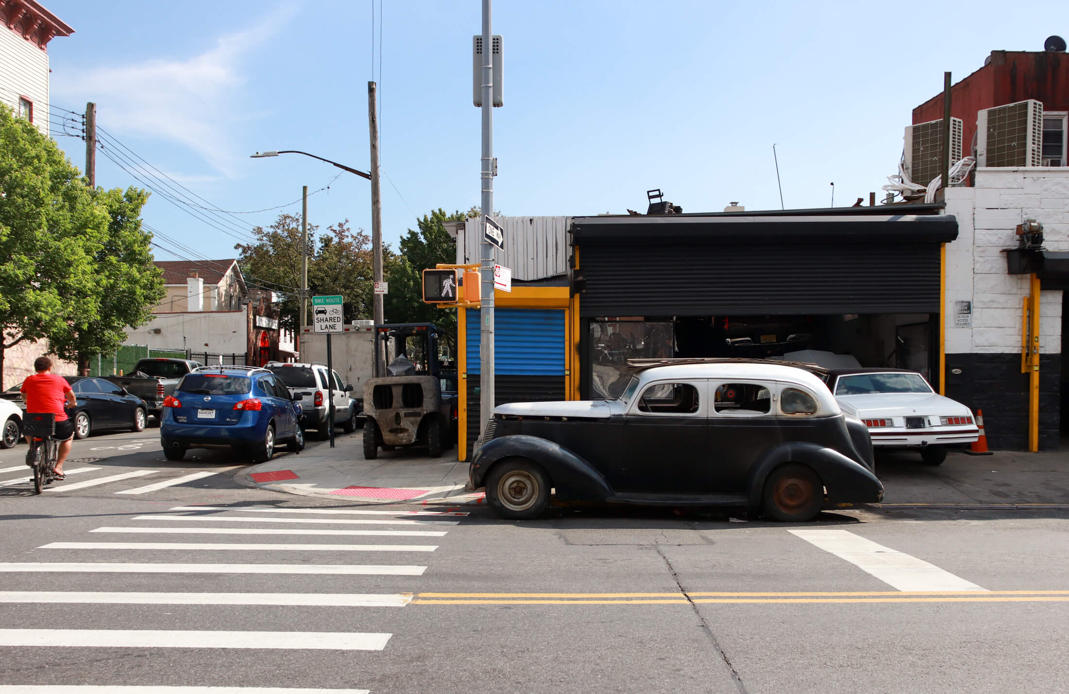 brooklyn - cyclist in a red shirt riding past a vintage car in east new york