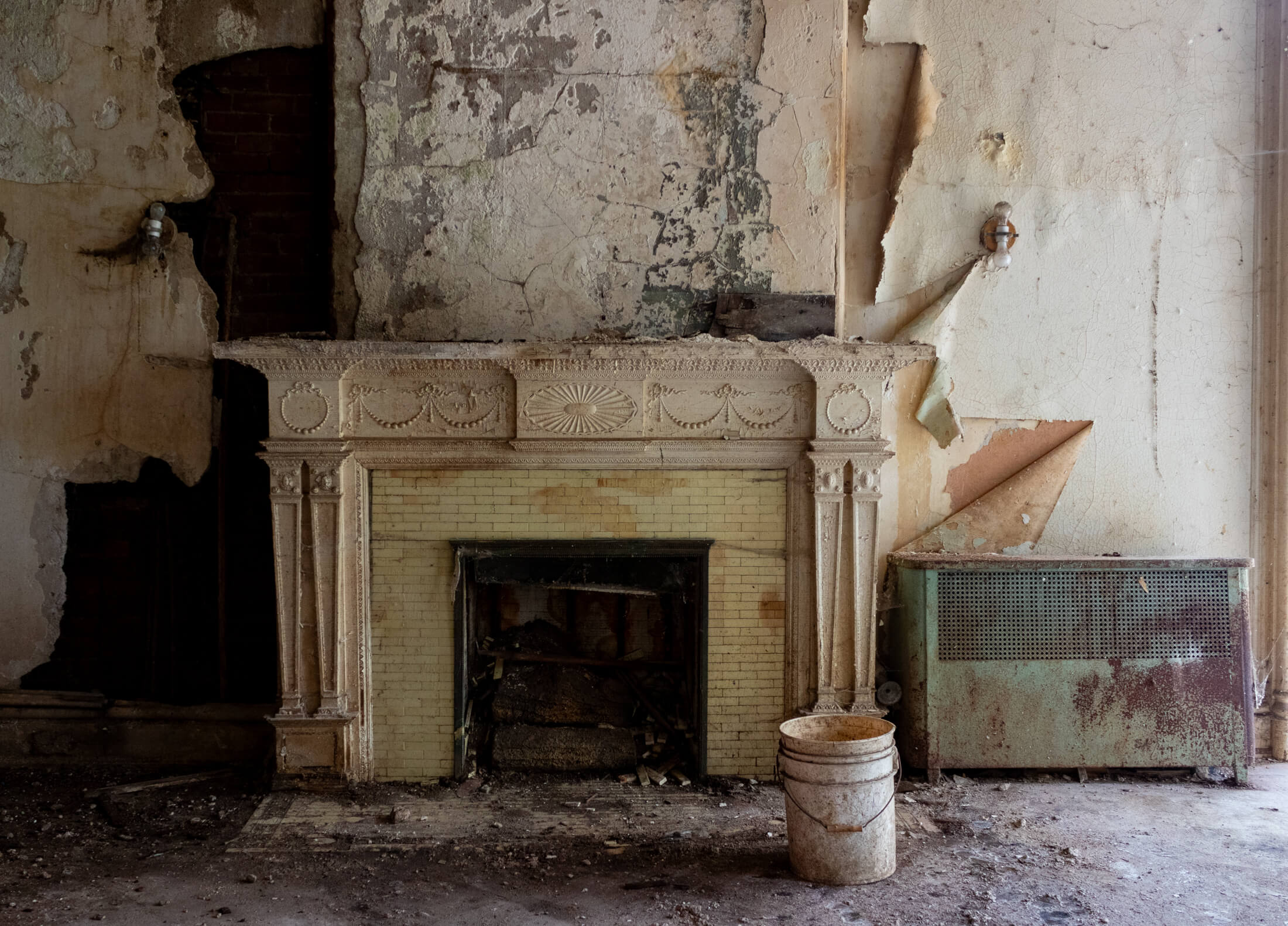 a colonial revival mantel with peeling wallpaper