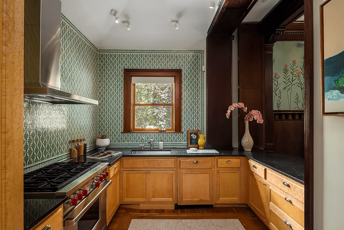 kitchen with decorative green tilework on the walls and a passthrough to the dining room