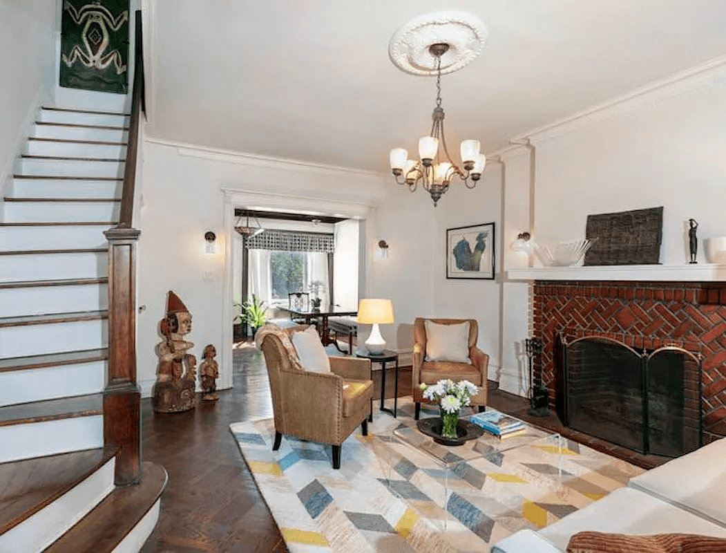 living room with brick mantel and view of stair with original newel post