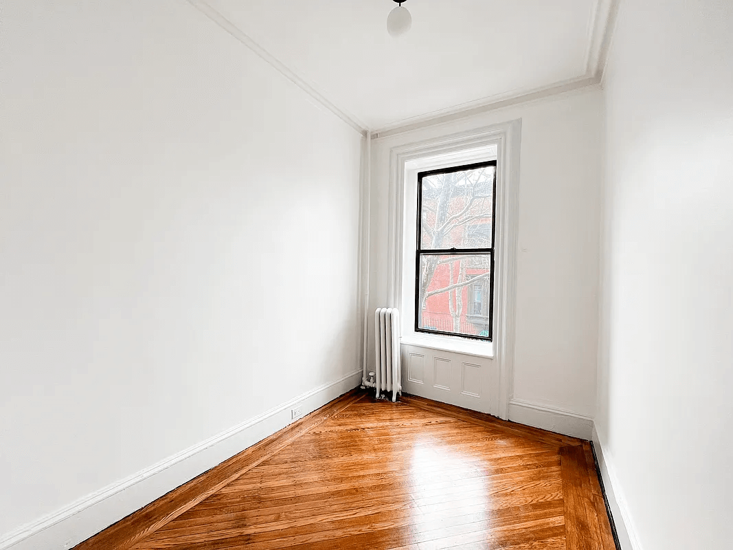 narrow bedroom with a radiator and one window