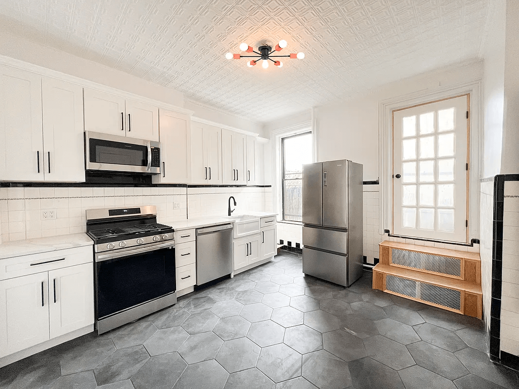 kitchen with gray tile floor, tin ceiling, and white cabinets