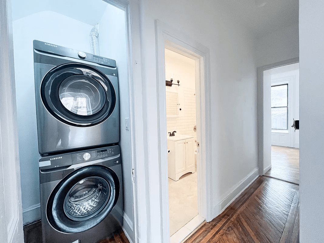 hallway with stacked washer and dryer in closet and a view of the white bathroom