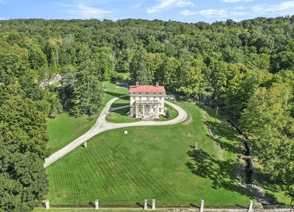 aerial view of house with circular drive and woods