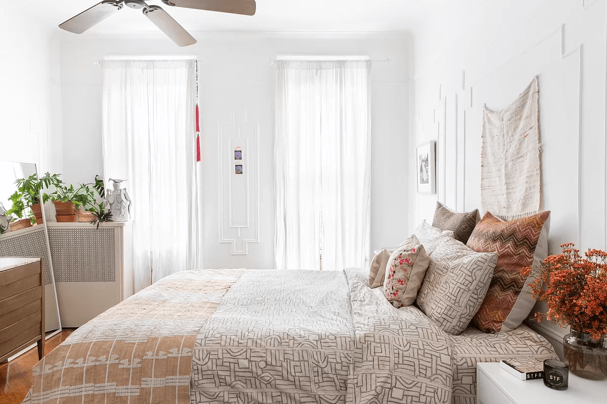 bedroom with two windows, wall moldings and a ceiling fan