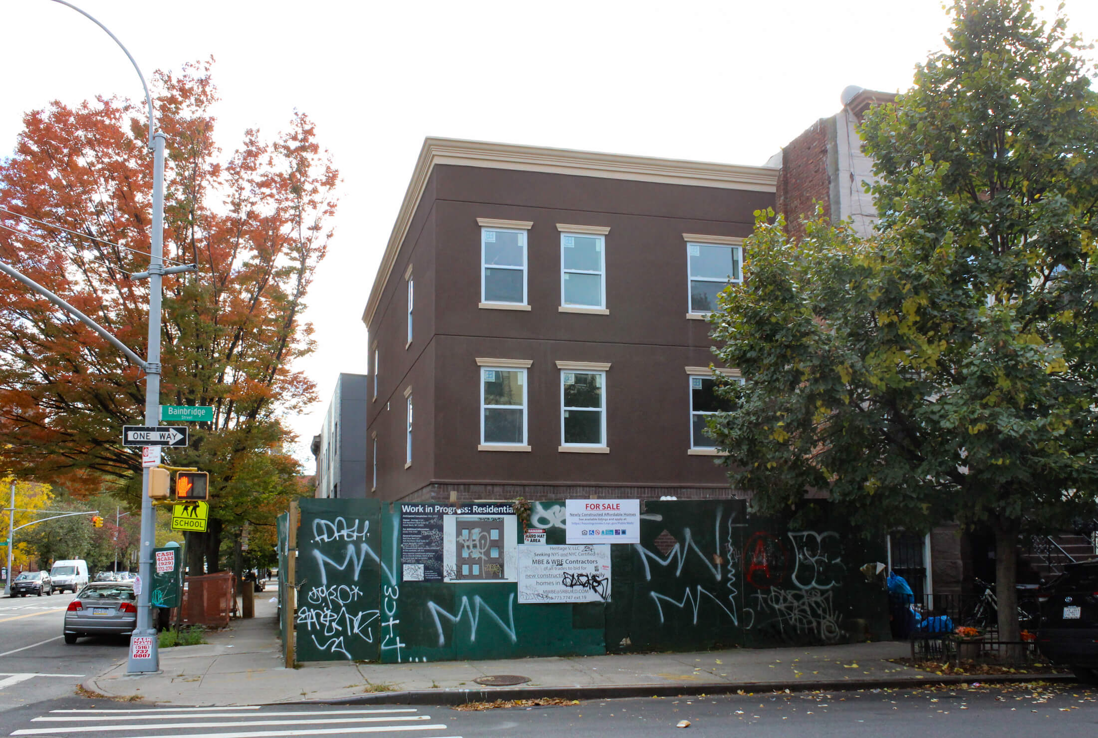 a brown stucco corner house behind a construction fence