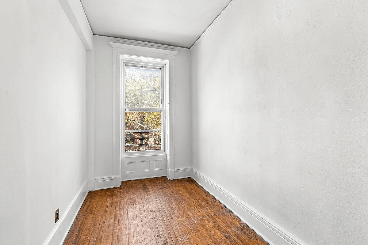 narrow bedroom or office in the top floor rental with one window and white walls