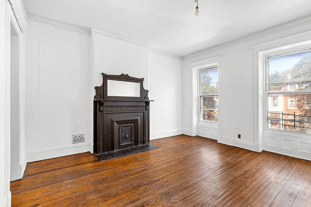 bedroom with wall moldings, wood floors and a mantel with a mirror
