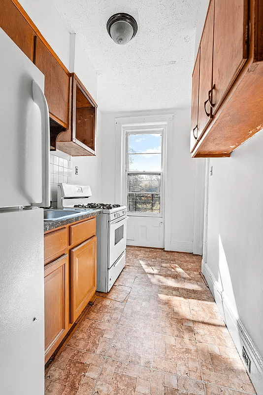 top floor kitchen with one window and wood cabinets