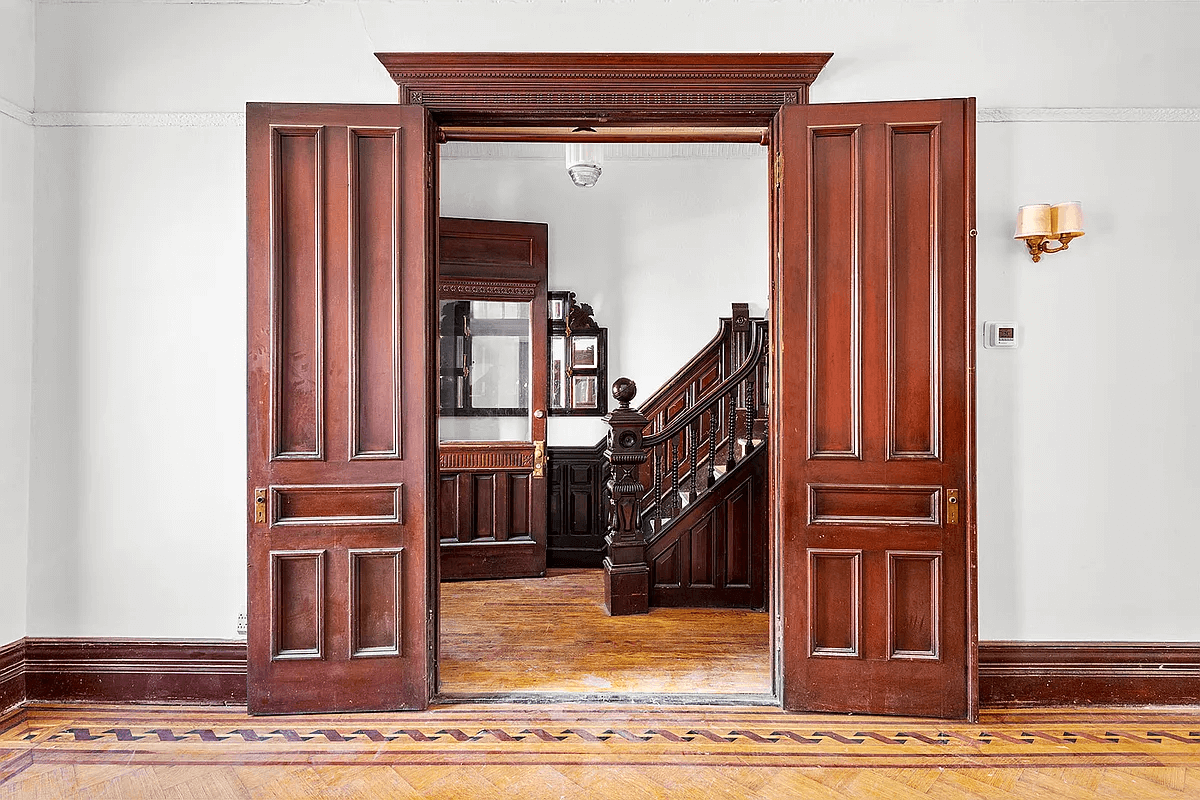 view through double parlor doors to entry hall with original stair and wainscoting