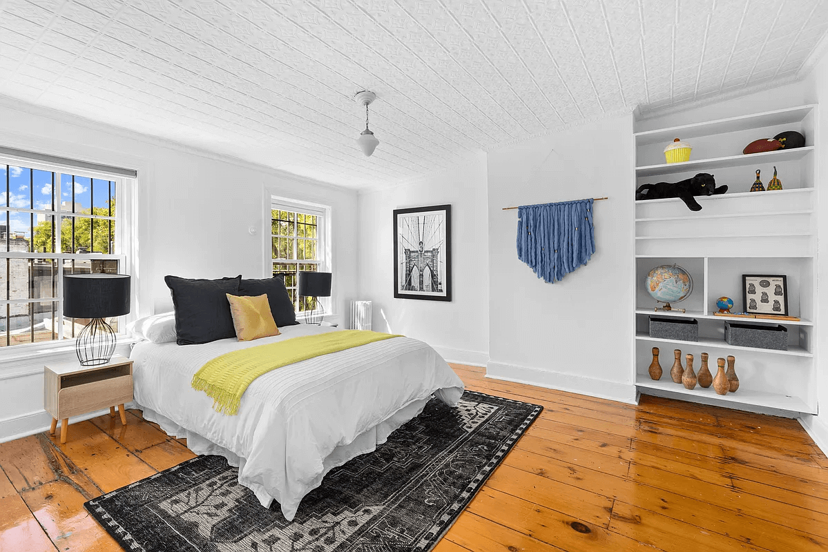 bedroom with wide planked floor boards and a tin ceiling