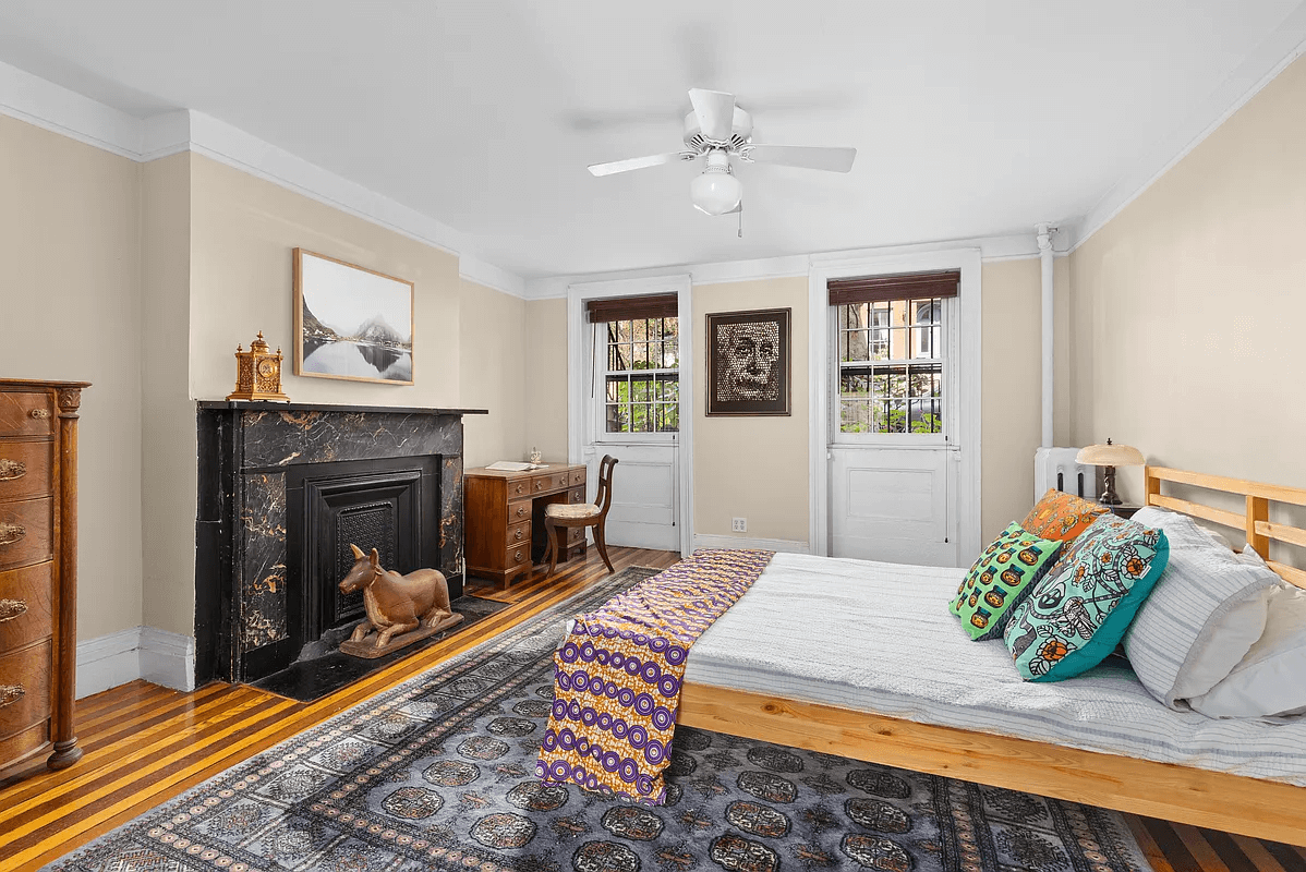 garden level bedroom with ceiling fan and black marble mantels