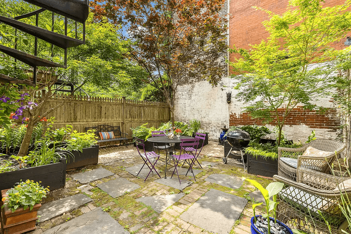 rear yard backing up to brick wall with a brick and stone patio