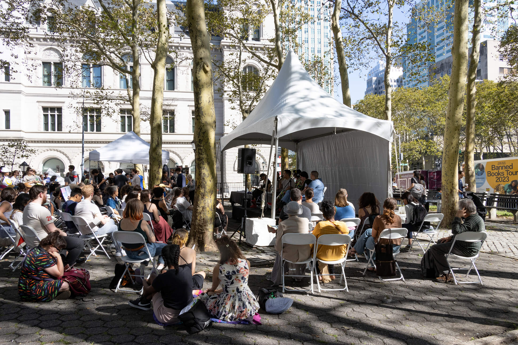 people sitting on foldling chairs to listen to an outdoor talk