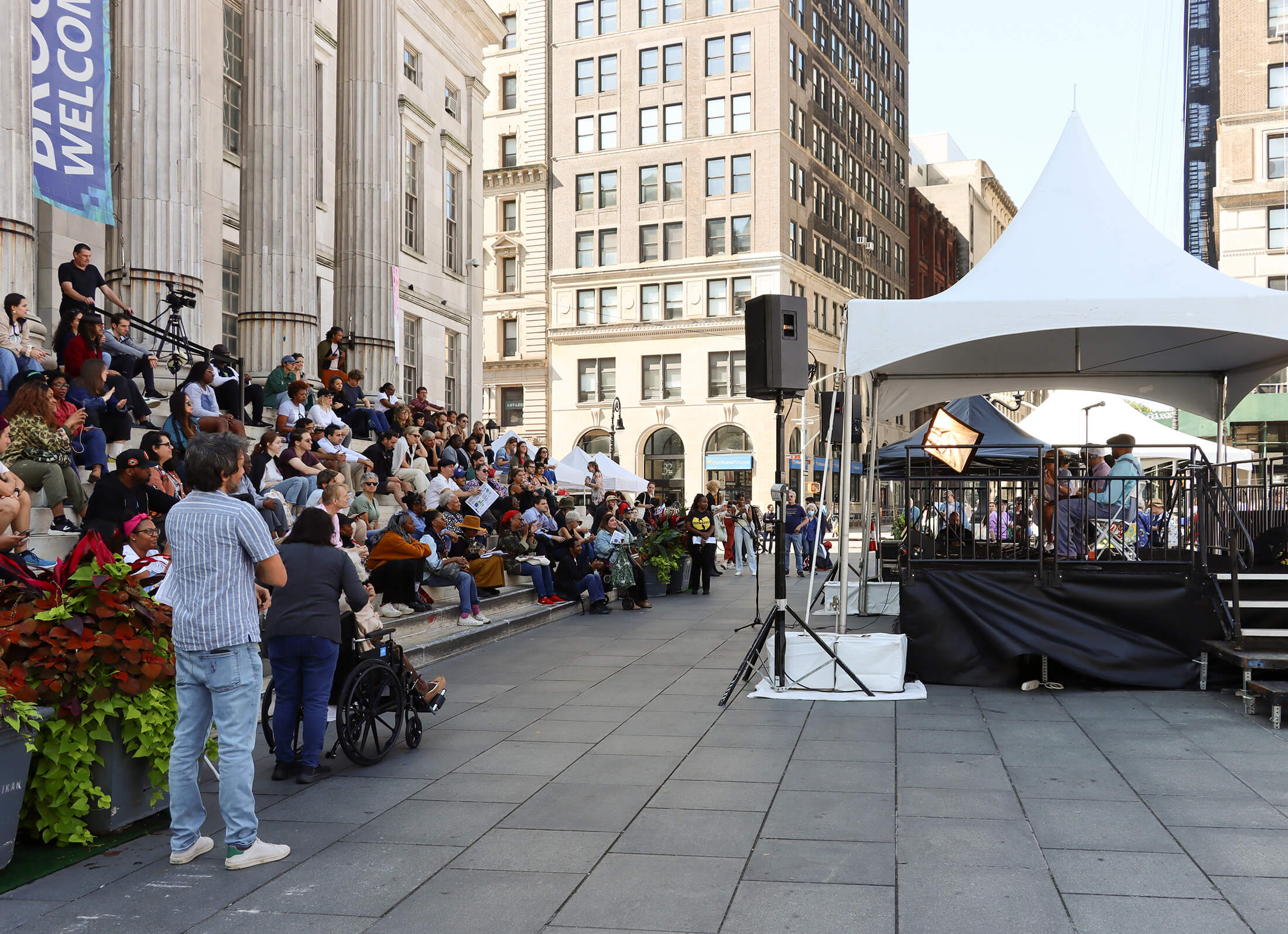 people sitting on the steps of brooklyn borough hall listening to a talk