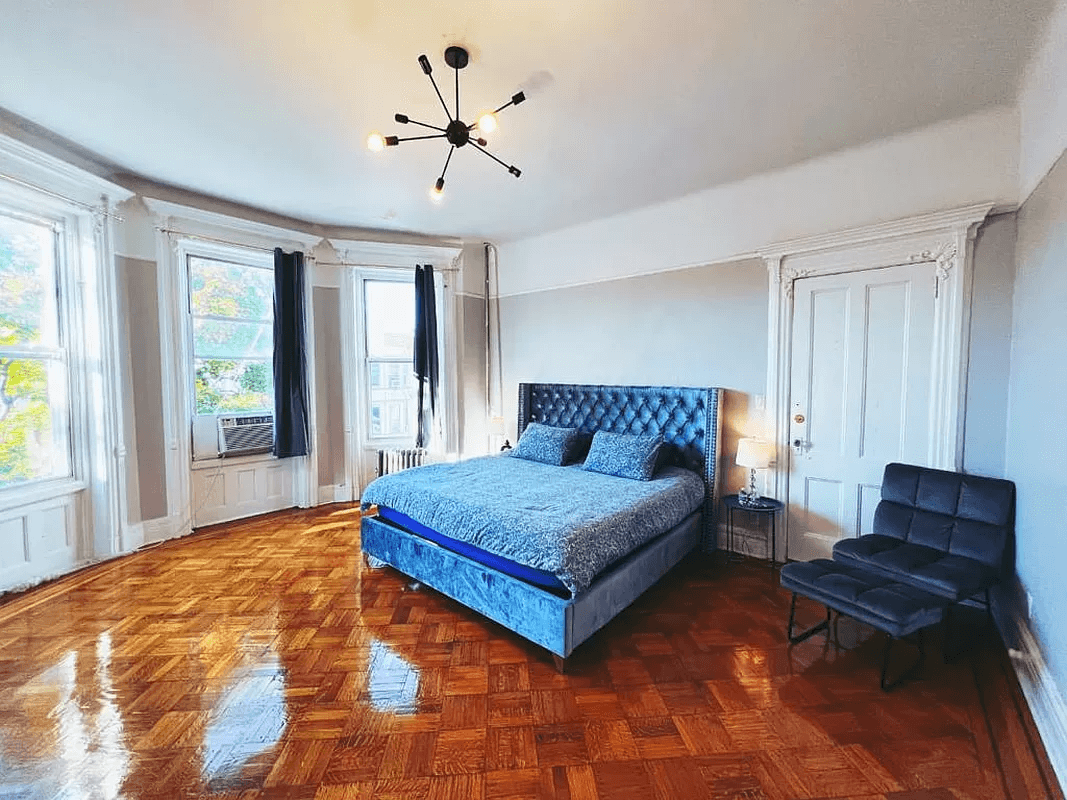 bedroom with moldings and three windows
