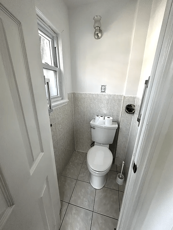 toilet room with gray tile and white toilet