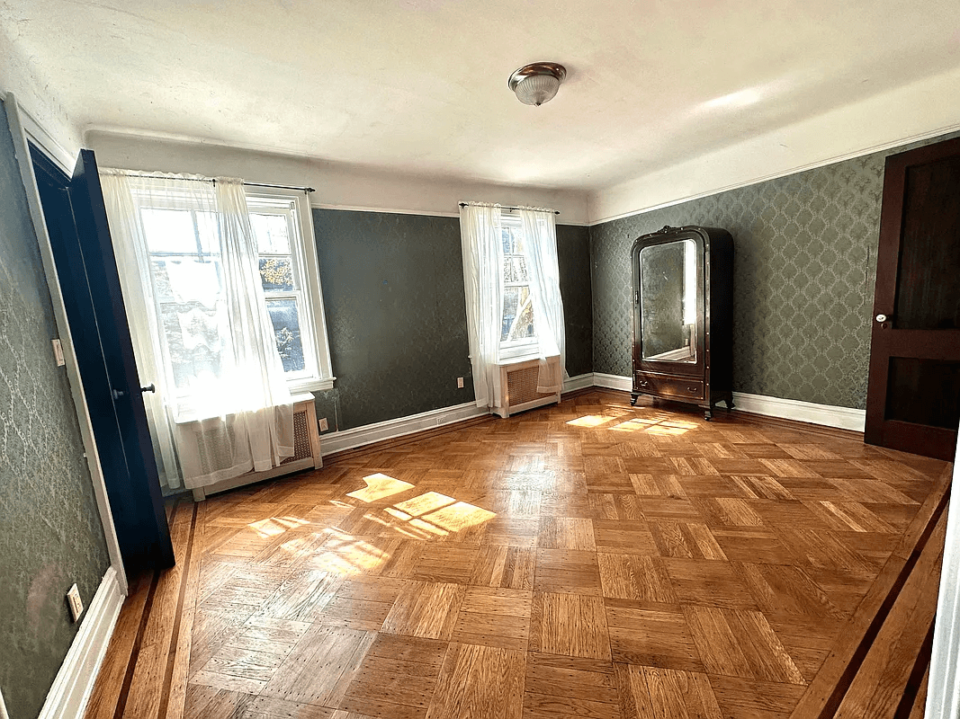 bedroom with green wallpaper and wood floor