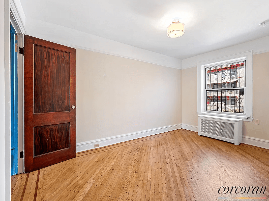 bedroom with wood floor and radiator under window