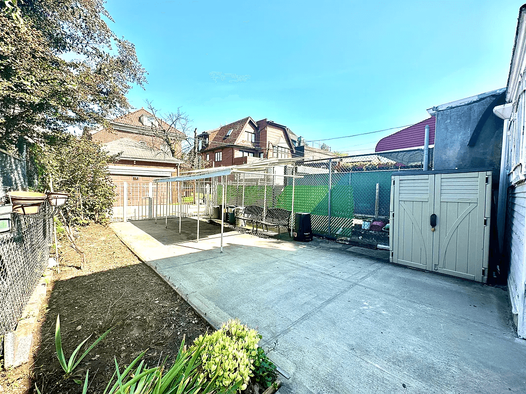 paved rear yard with a planting bed along one side