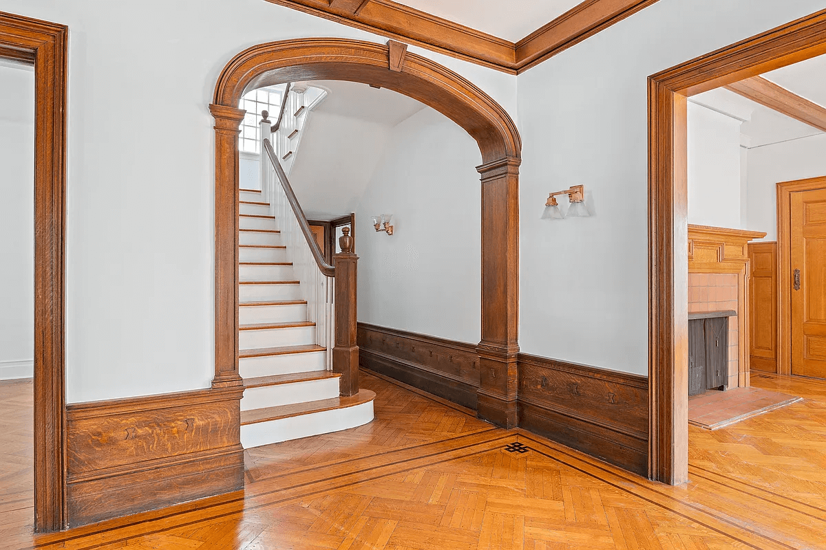 entry with wood trimmed arch and original stair