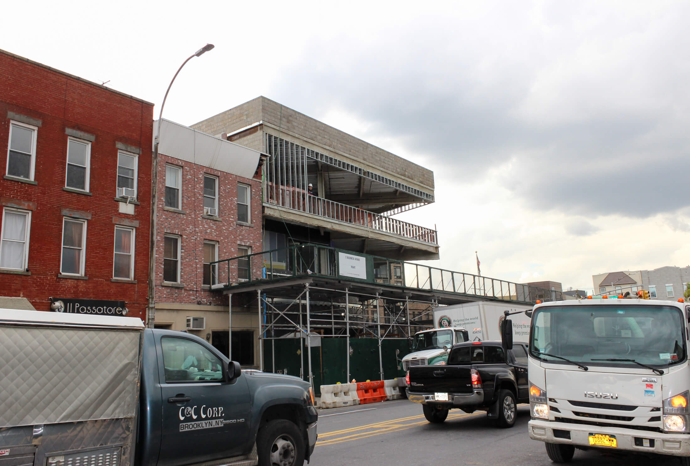 cars and trucks driving by a building under construction