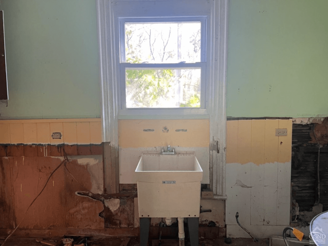kitchen with a plastic slop sink and torn out wainscoting