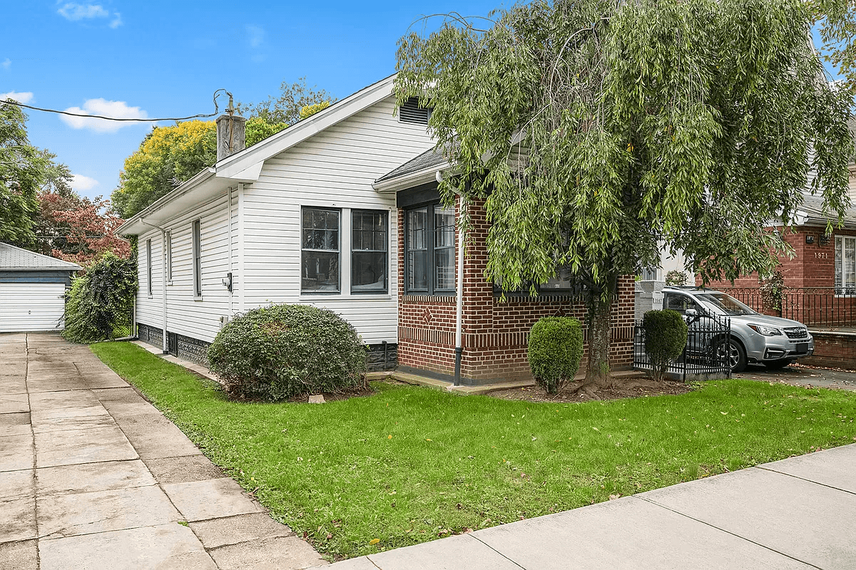 single story white clapboard house with a brick vestibule