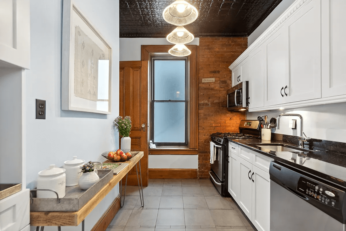 kitchen with tile floor, white cabinets and dark painted tin ceiling