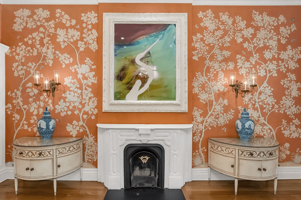 dining room with orange wall covering and a white mantel