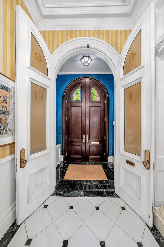 double front doors opening into a marble-tiled vestibule