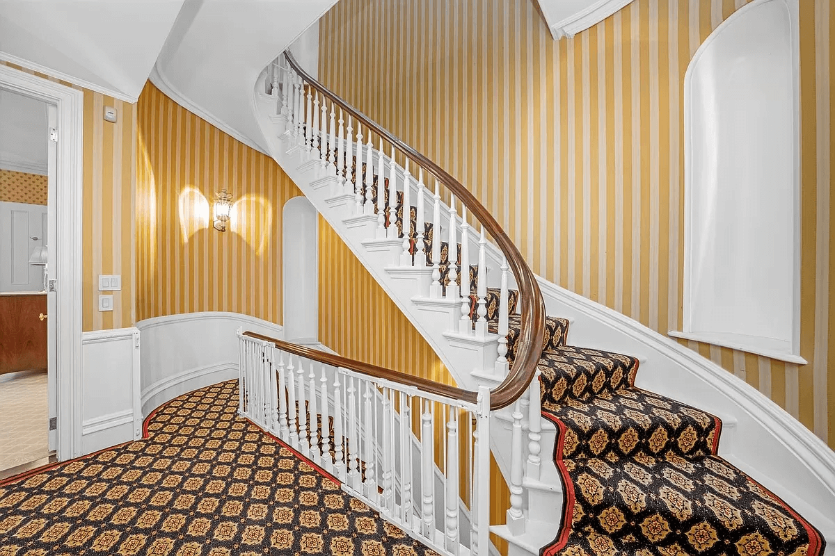 upper hall with yellow striped wallpaper and patterned carpet