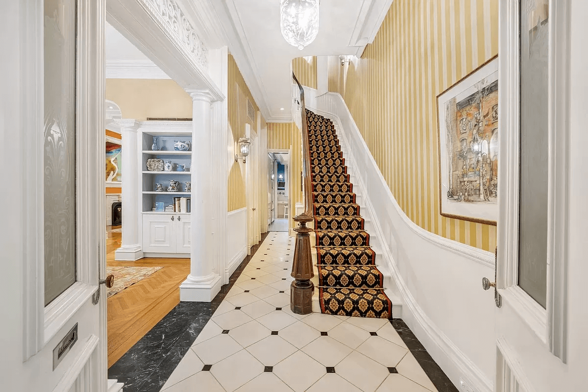 entry with yellow striped wallpaper and stair with wooden newel post