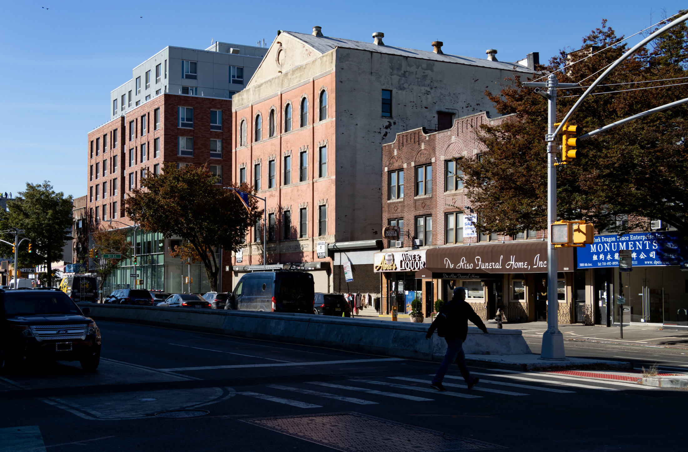 a person walking across 4th avenue with a view of the new brick library beyond