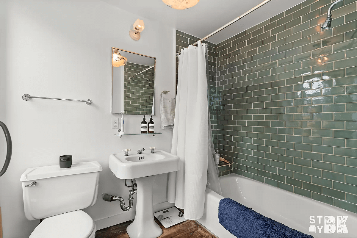 bathroom with green subway tile surrounding the bath